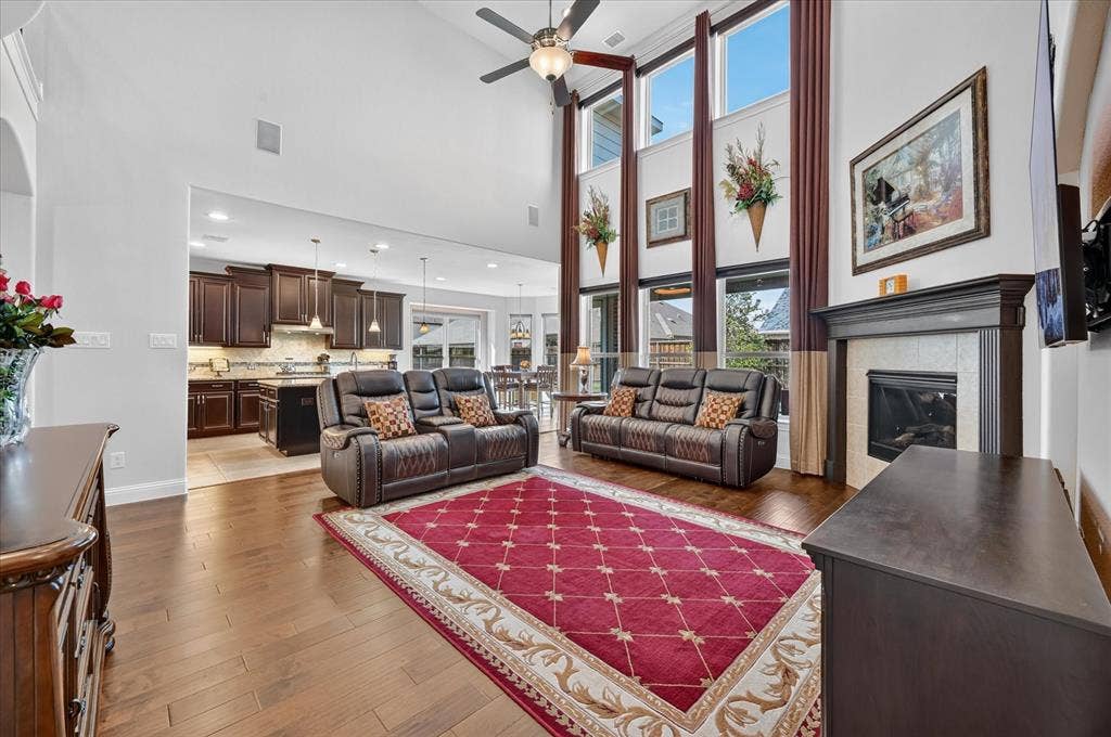 Soaring ceilings with transom windows, wood-finish flooring, a built-in fireplace with mantel, and recessed lighting