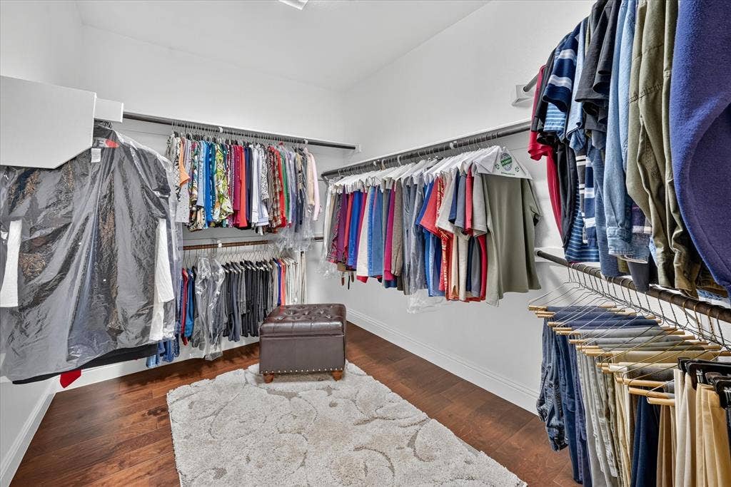 Walk-in closet with extensive storage, multiple hanging rods, wire shelving, and wood-finish flooring