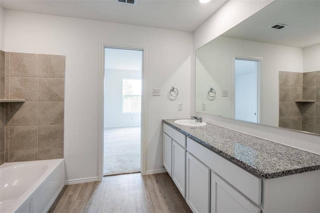 1708 Sims Street, McKinney, TX 75071 Bathroom featuring hardwood / wood-style floors, vanity, and a tub to relax in