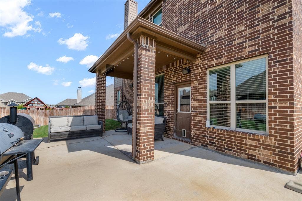 3605 Barby Court, Midlothian, TX 76065 Covered patio featuring a concrete surface, brick columns, string lighting, and an exterior door with a pet access panel