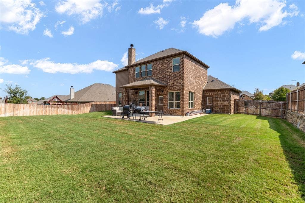 3605 Barby Court, Midlothian, TX 76065 Expansive backyard featuring a manicured lawn, full brick exterior, a covered patio, and a privacy fence