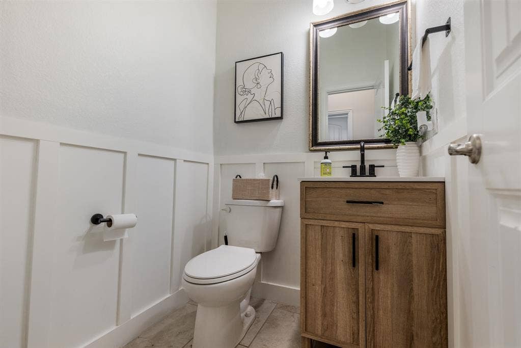 3605 Barby Court, Midlothian, TX 76065 Spa-inspired bathroom featuring a wood-finish vanity with ample storage, black hardware accents, and a framed mirror with integrated lighting