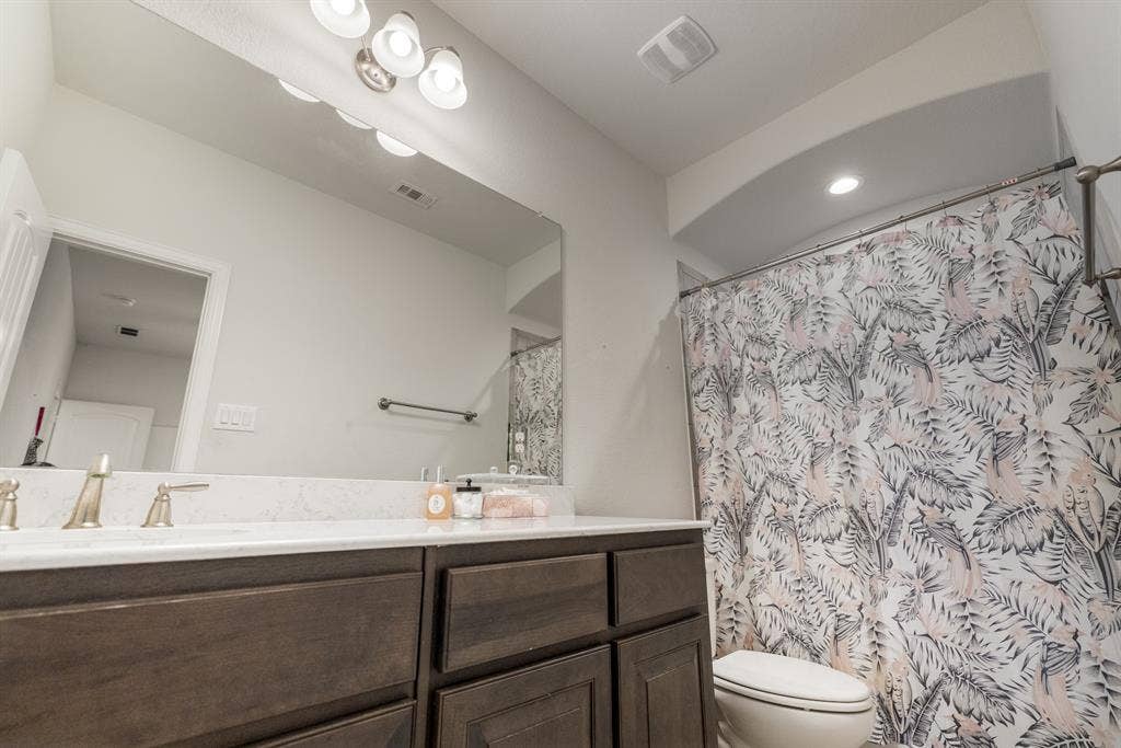 3605 Barby Court, Midlothian, TX 76065 Full vanity mirror with decorative light fixture, white countertop, dark wood-finish cabinetry, and brushed nickel faucet