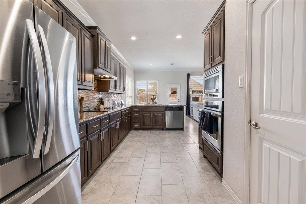 3605 Barby Court, Midlothian, TX 76065 Stainless steel appliances, built-in oven and microwave, dark wood cabinetry, tile flooring, and granite countertops