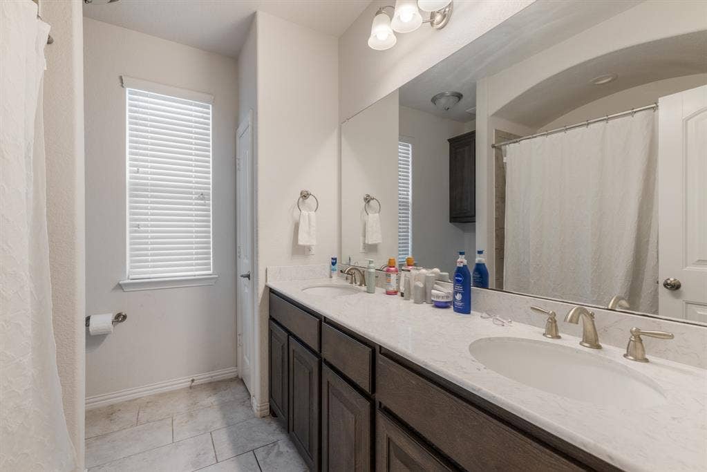 3605 Barby Court, Midlothian, TX 76065 Dual vanity with brushed nickel fixtures, white countertop, dark wood-finish cabinetry, and tiled flooring