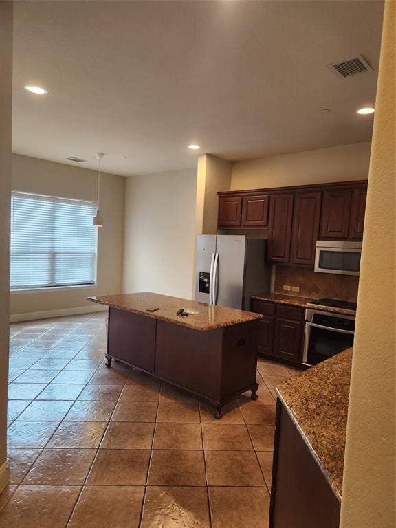 5720 Robbie Road, Plano, TX 75024 Kitchen featuring an island with stone-finish countertop, stainless steel appliances, dark wood-finish cabinetry, tile flooring, and recessed lighting