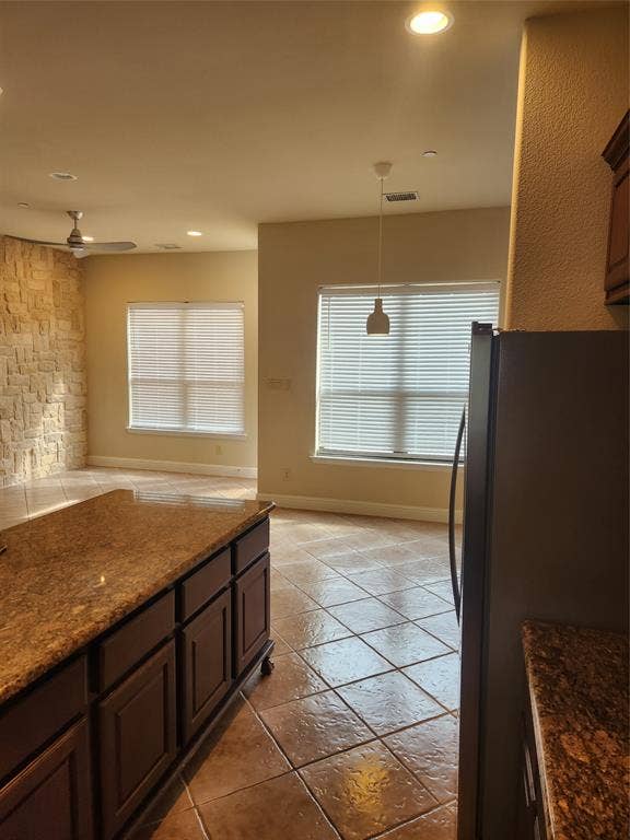 5720 Robbie Road, Plano, TX 75024 Built-in kitchen island with stone countertop, recessed lighting, ceiling fan, and stone accent wall