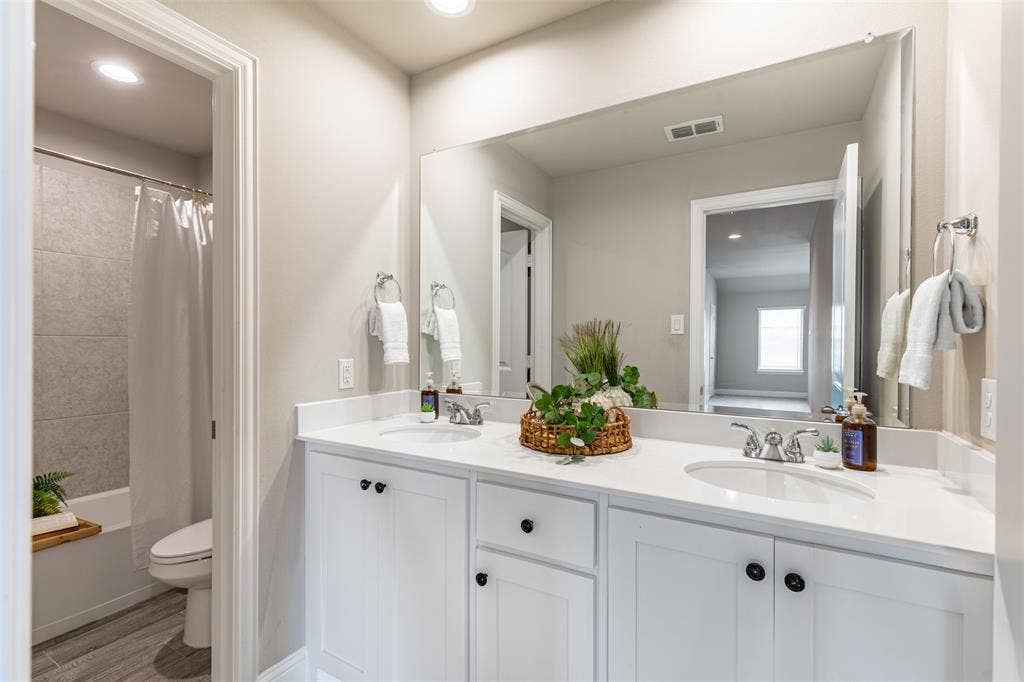 405 Rosie Court, Argyle, TX 76226 Upstairs bathroom with a spacious double vanity and ample cabinetry, thoughtfully separated by a privacy door from the shower/tub combination and the double vanity area.