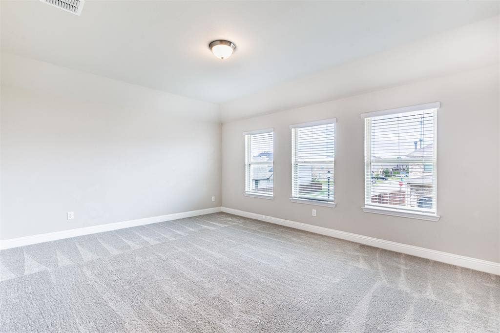 405 Rosie Court, Argyle, TX 76226 Spacious second-floor game room with large windows, abundant natural light, and comfortable carpeting—perfect for entertaining, recreation, or a media space.
