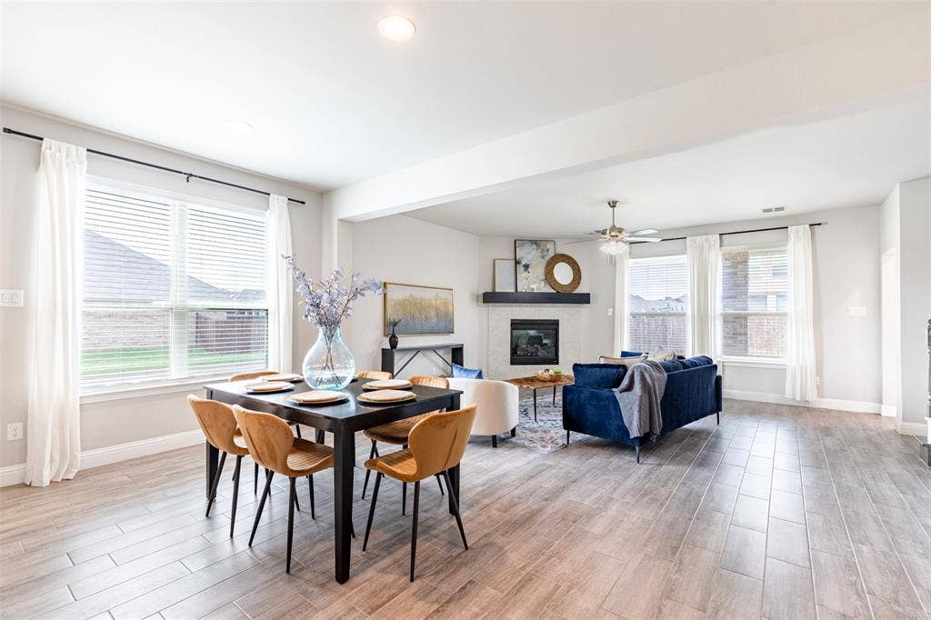 405 Rosie Court, Argyle, TX 76226 Open-concept eat-in kitchen and living room filled with natural light, featuring a gas fireplace with log insert and ceiling fan for comfortable everyday living.