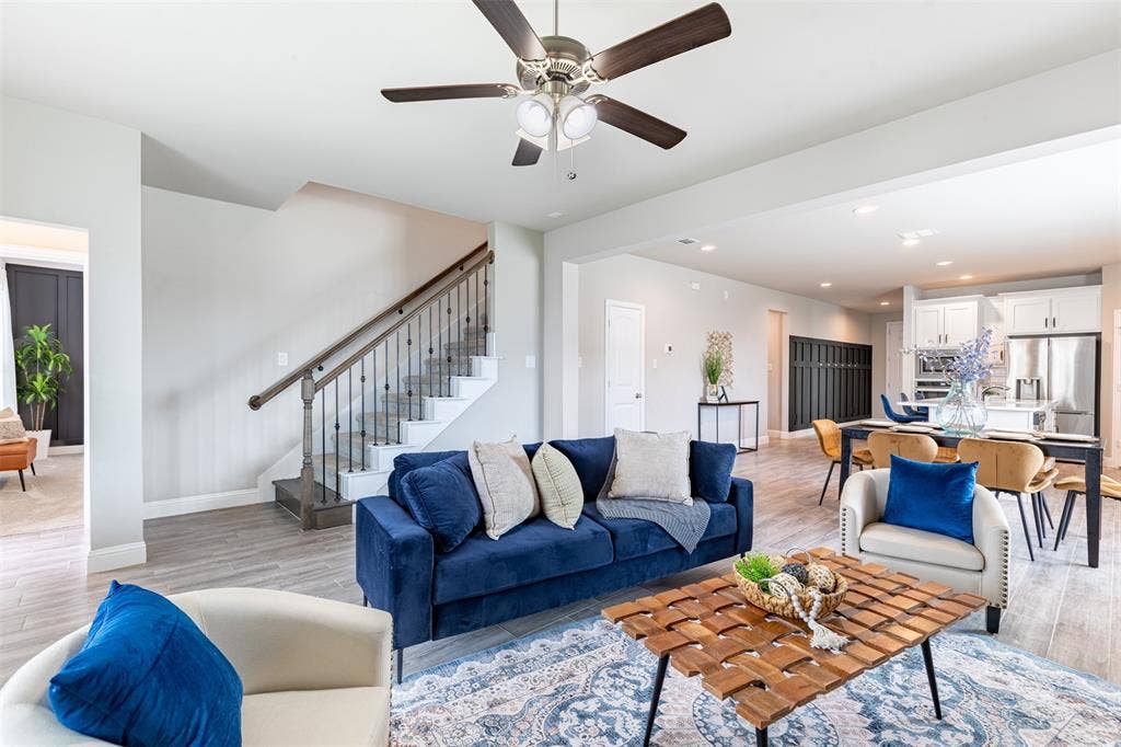405 Rosie Court, Argyle, TX 76226 Spacious living room with upgraded iron stair railing, providing access to the second floor and a convenient hallway leading to the primary suite and backyard.