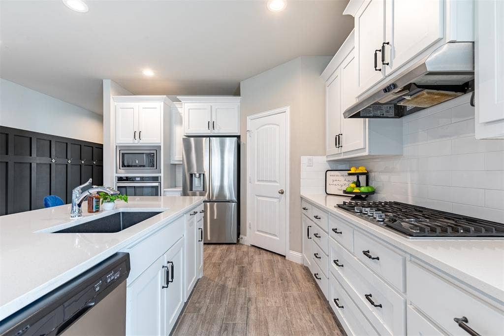 405 Rosie Court, Argyle, TX 76226 Well-appointed kitchen workspace featuring a farmhouse sink, 5-burner cooktop, ample cabinetry, walk-in pantry, refrigerator, and built-in oven with microwave.