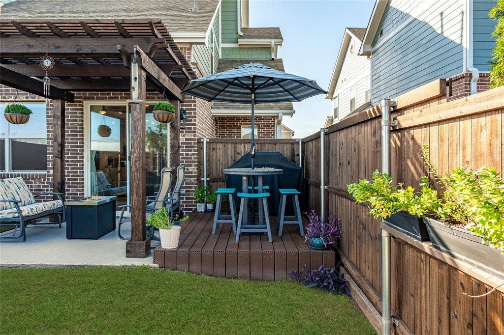 Outdoor living area featuring a covered timber pergola, concrete patio, elevated wood-finish deck, and wood privacy fencing