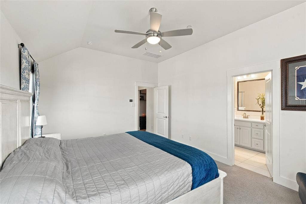 Vaulted ceiling featuring a ceiling fan with integrated lighting and neutral carpeting