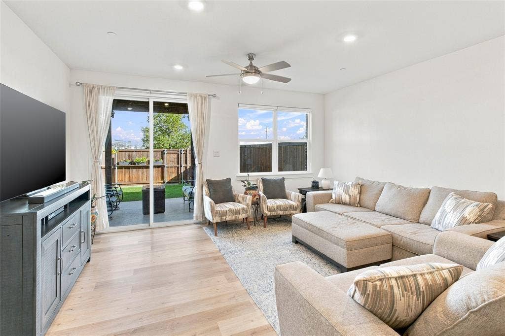 Living area featuring light-toned wood-finish flooring, recessed lighting, a ceiling fan with integrated light fixture, and large sliding glass doors providing outdoor access