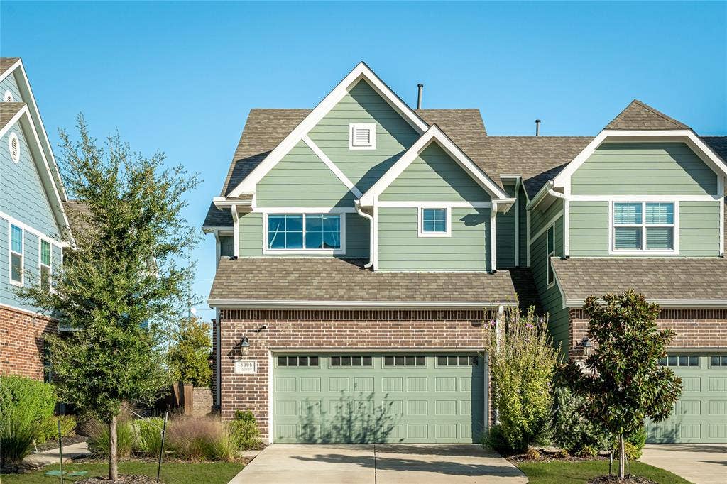 Multi-story residence featuring horizontal lap siding, a brick facade, asphalt shingle roofing, and a multi-car garage with a paneled door