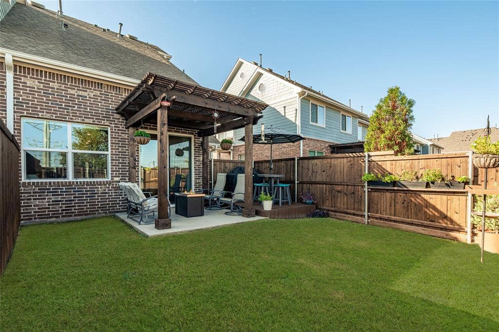 Backyard featuring a concrete patio with a wooden pergola, privacy wood fencing, and a manicured lawn