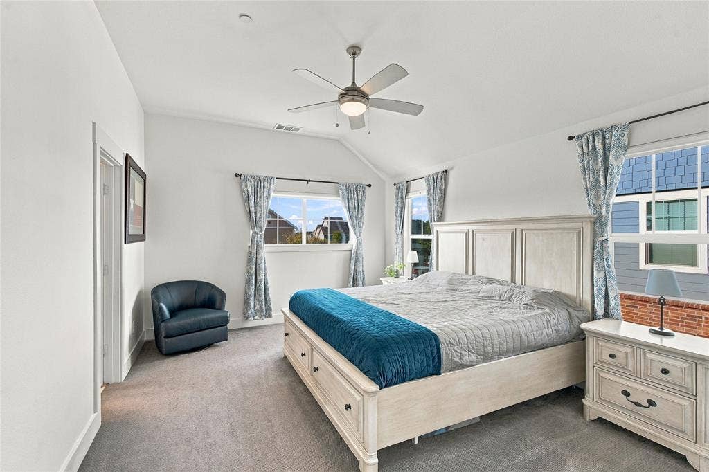 Vaulted ceilings featuring a central light-integrated ceiling fan, neutral wall-to-wall carpeting, and multiple dual-pane windows with grid detailing