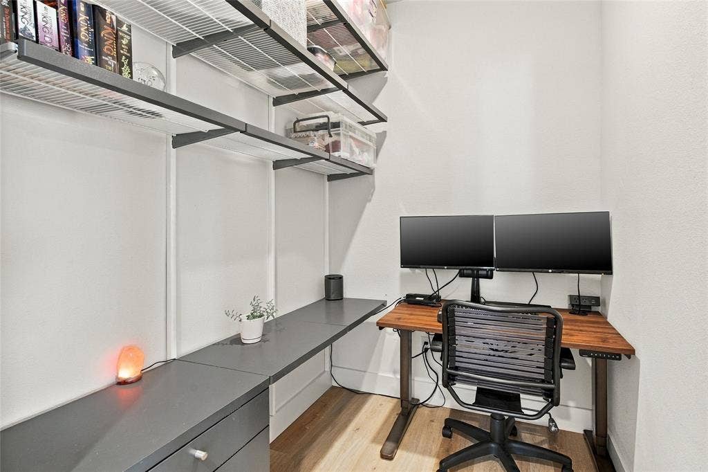 Built-in charcoal cabinetry with integrated desk surface, wood-finish flooring, and tiered white wire shelving