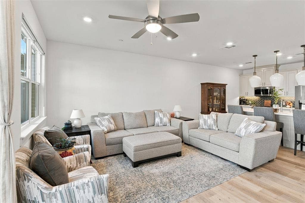 Open-concept interior featuring light wood-finish flooring, recessed lighting, and a ceiling fan with integrated illumination