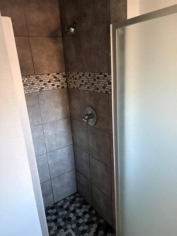 Tiled shower enclosure with a mosaic accent band and hexagonal floor tiles