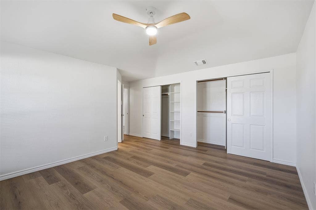 661 Thompson Drive, Coppell, TX 75019 Vaulted ceiling, wood-finish flooring, ceiling fan with integrated lighting, built-in closet shelving, and sliding closet doors