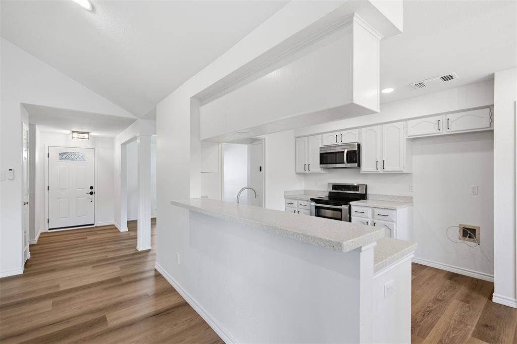 661 Thompson Drive, Coppell, TX 75019 Kitchen featuring white cabinetry, stainless steel microwave, and range with a light-toned countertop