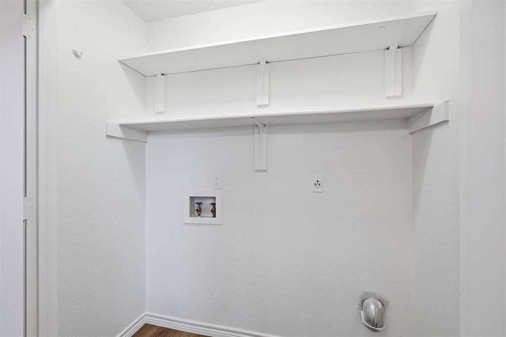 661 Thompson Drive, Coppell, TX 75019 White interior walls with two white wall-mounted shelves, wood-finish flooring, and utility hookups