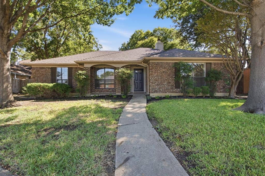 661 Thompson Drive, Coppell, TX 75019 Brick ranch home featuring a welcoming front facade with arched entryway, mature landscaping, and a manicured lawn