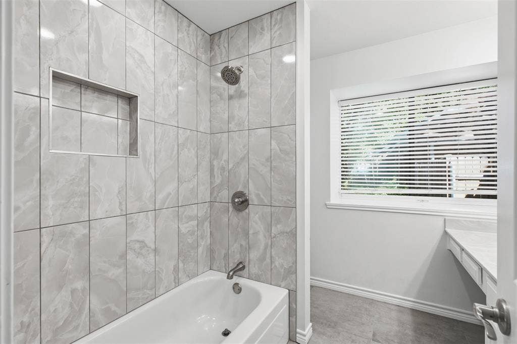 661 Thompson Drive, Coppell, TX 75019 Bathtub with grey tiled surround, built-in shower niche, and brushed nickel fixtures