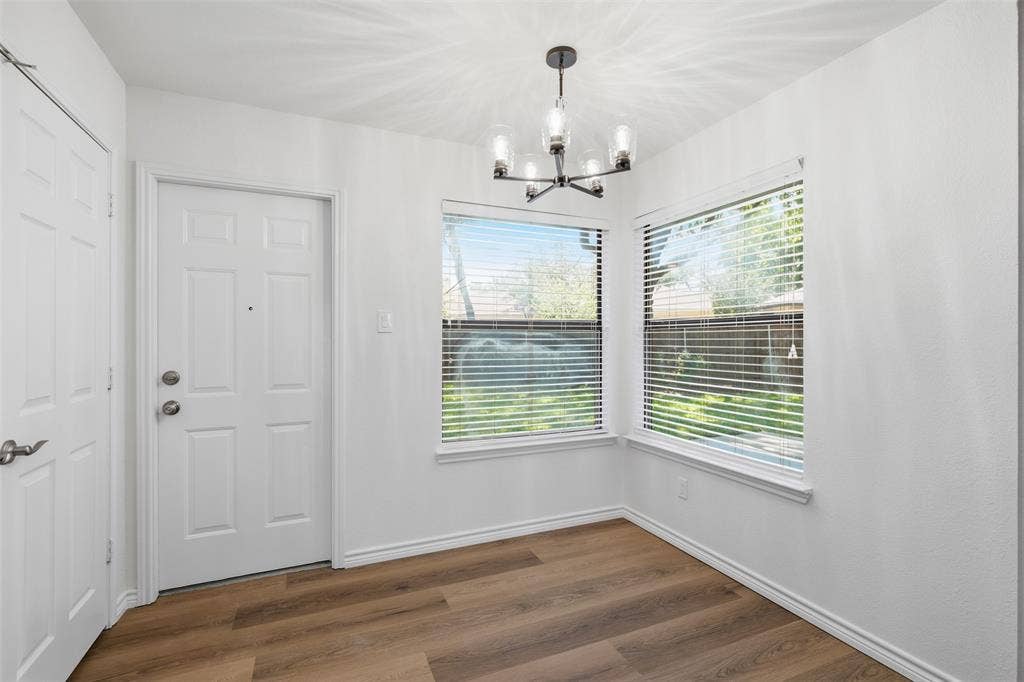 661 Thompson Drive, Coppell, TX 75019 White paneled door, wood-finish flooring, two windows with blinds, and a modern chandelier