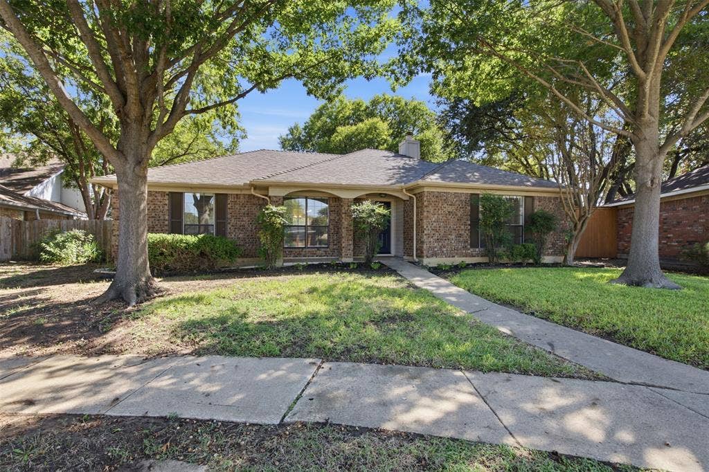 661 Thompson Drive, Coppell, TX 75019 Brick exterior with a gabled roof and mature trees framing the property