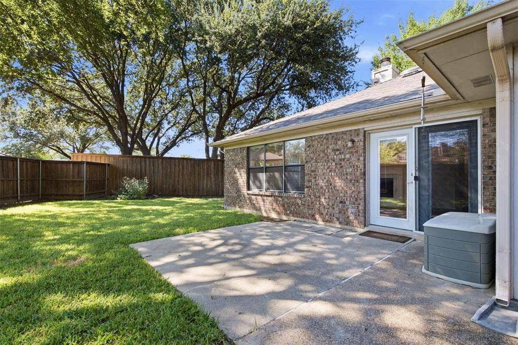 661 Thompson Drive, Coppell, TX 75019 Brick exterior with expansive concrete patio overlooking a manicured lawn anchored by mature shade trees