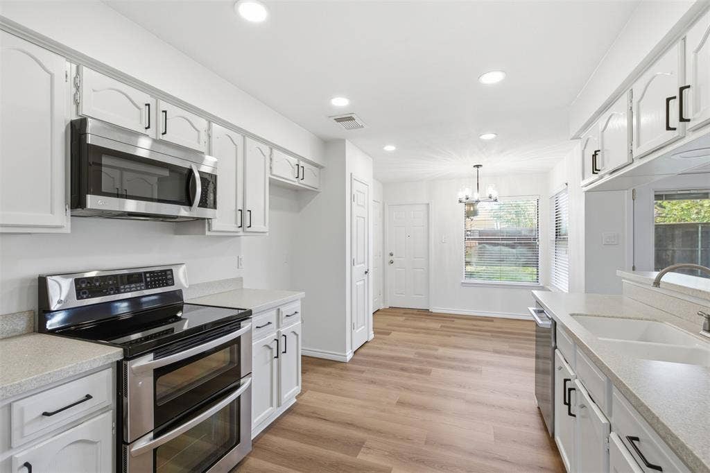 661 Thompson Drive, Coppell, TX 75019 Kitchen featuring wood-finish flooring, white cabinetry with black hardware, stainless steel appliances, and recessed lighting