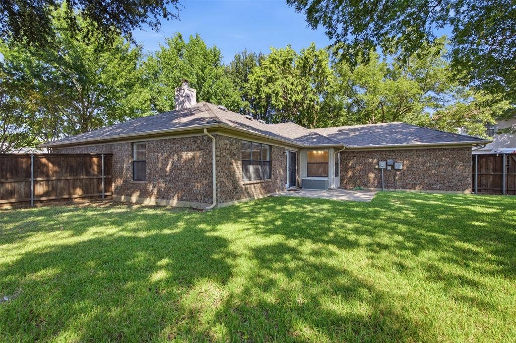 661 Thompson Drive, Coppell, TX 75019 Spacious backyard featuring a manicured lawn, brick exterior, and a concrete patio