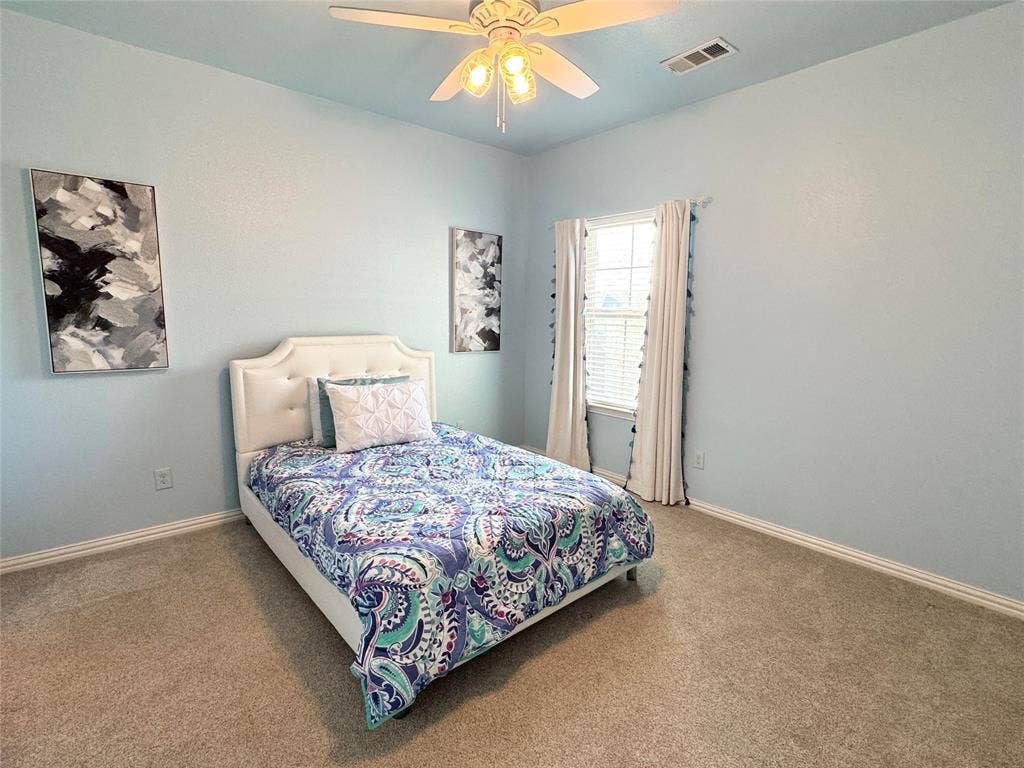 Carpeted flooring, multi-pane window with grid detailing, and a central ceiling fan with multi-light fixture