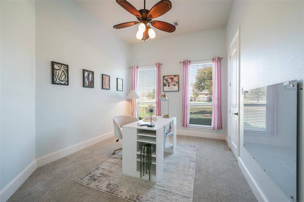 High-ceiling room featuring neutral carpeting, two windows with blinds, and a multi-blade ceiling fan with integrated lighting