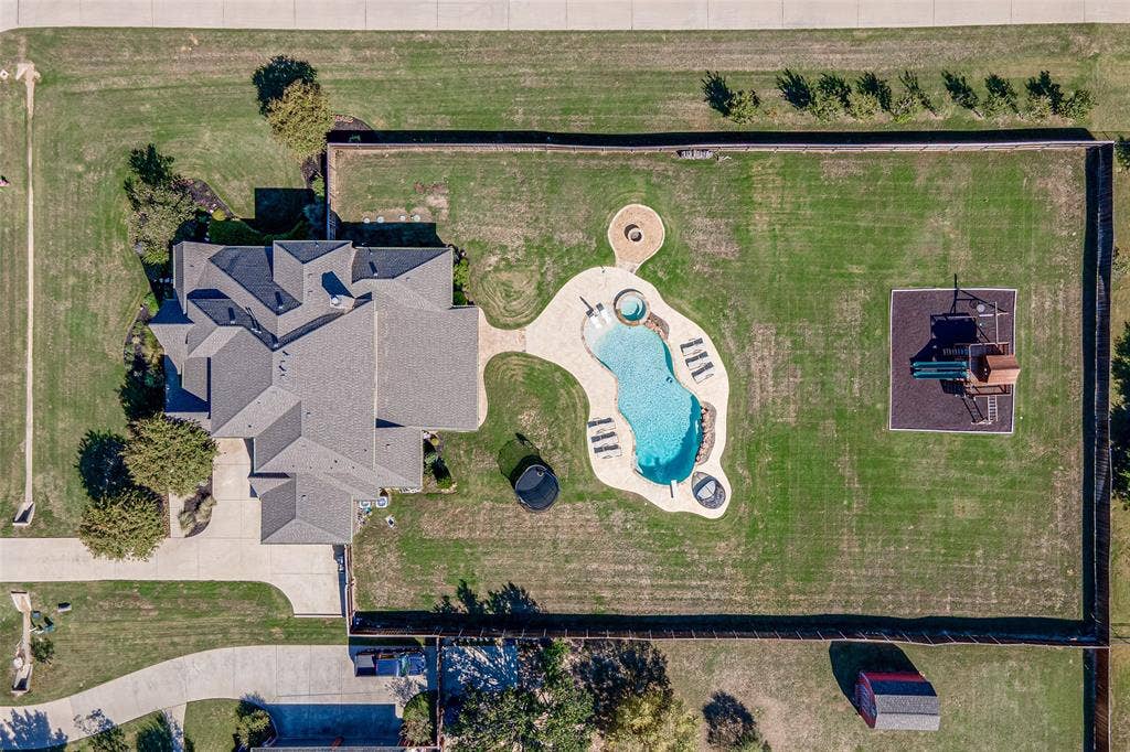Expansive lot featuring an inground swimming pool, integrated spa, circular fire pit, and a perimeter fence