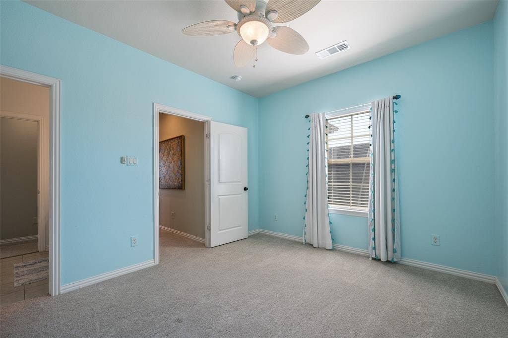 Neutral carpeting, ceiling-mounted paddle fan with integrated lighting, and a multi-pane window with horizontal blinds
