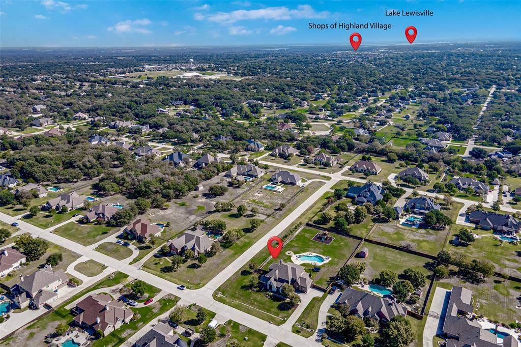Aerial perspective of a multi-acre residential lot featuring a multi-gabled roofline, private swimming pool, concrete driveway, and expansive lawn area