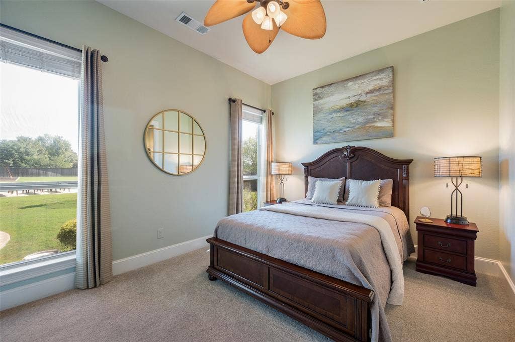 High ceilings featuring a multi-blade ceiling fan with integrated lighting, expansive windows with window treatments, and neutral carpeting