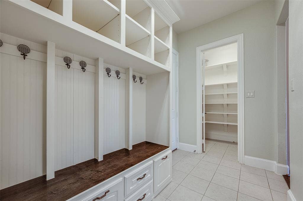 Built-in mudroom cabinetry featuring beadboard paneling, upper cubbies, dark wood-finish bench seating, and lower storage drawers with metallic hardware
