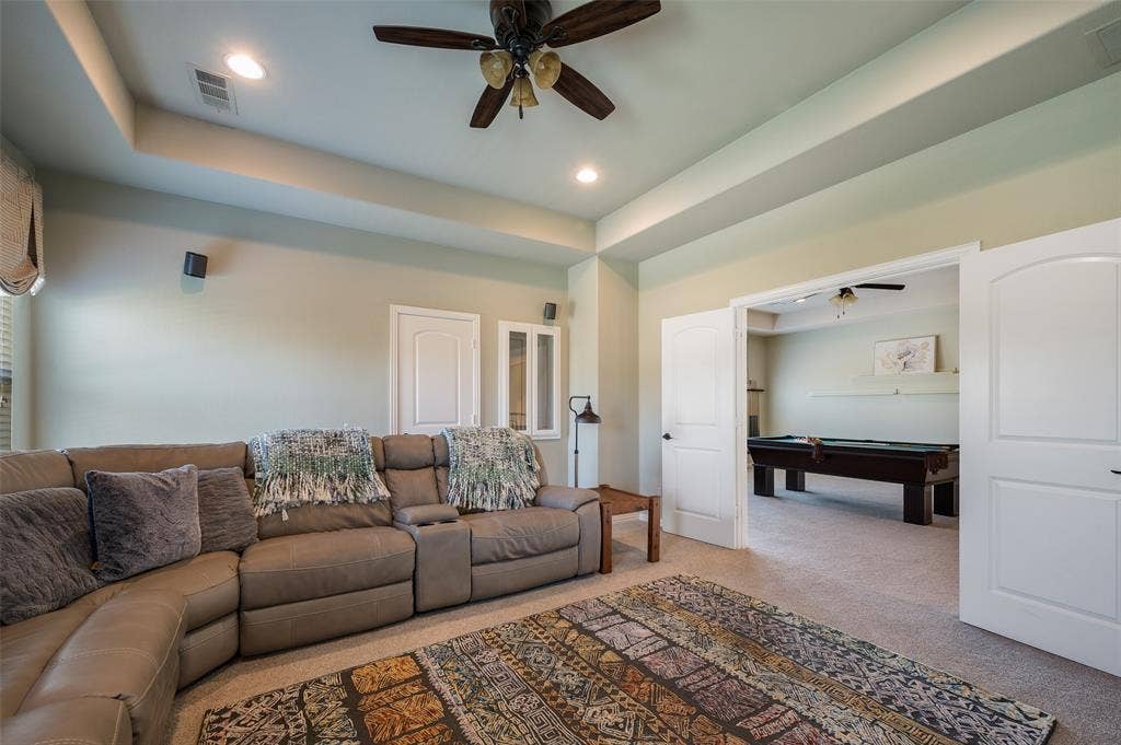 Tray ceiling featuring a central ceiling fan with integrated lighting, neutral wall paint, recessed lighting, and dual arched-panel interior doors