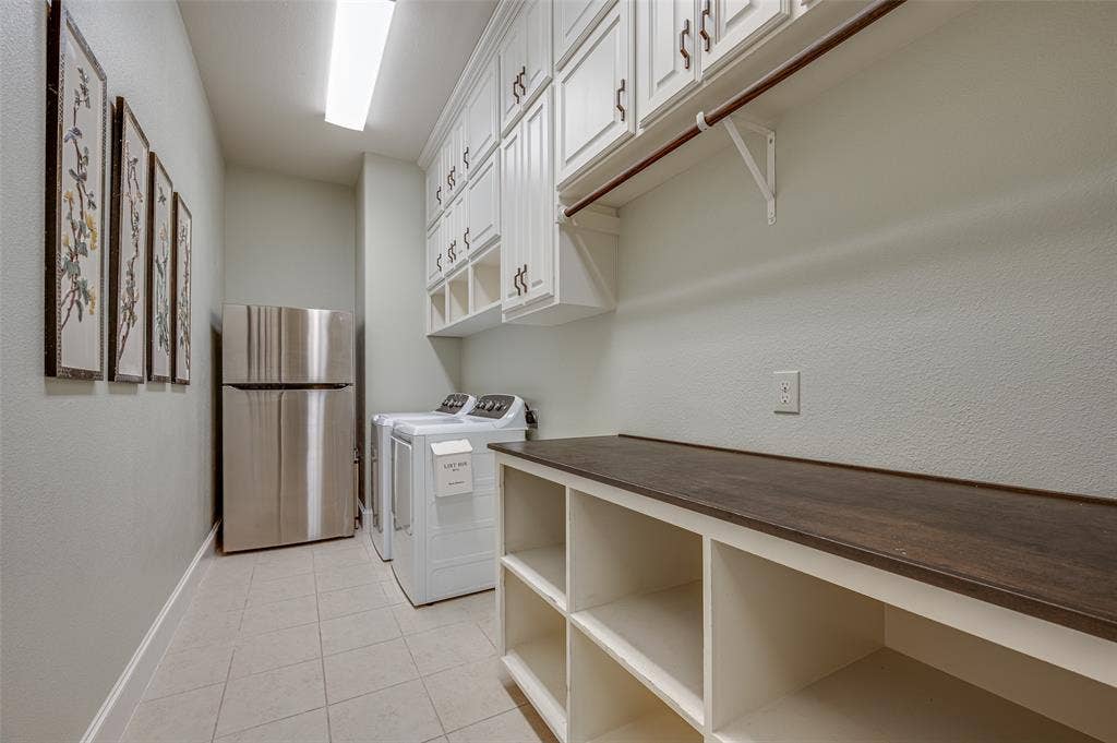 Custom cabinetry featuring upper wall-mounted storage and lower open shelving with a wood-finish countertop, tile flooring, and integrated clothes rod
