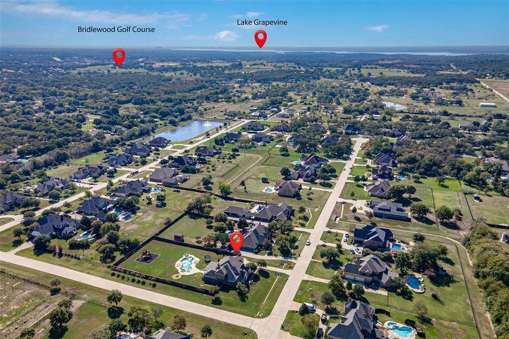 Aerial perspective of a residential property featuring an in-ground swimming pool, expansive fenced backyard, and mature landscaping