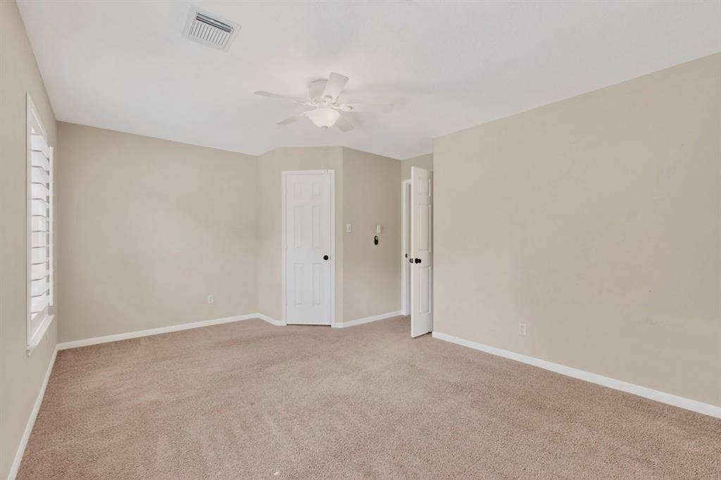 Plush carpet flooring, neutral paint tones, recessed ceiling fan, white interior doors, and window with plantation shutters