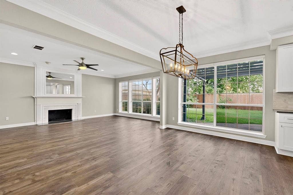 Spacious room with wood-finish flooring, a white mantel fireplace, and a ceiling fan