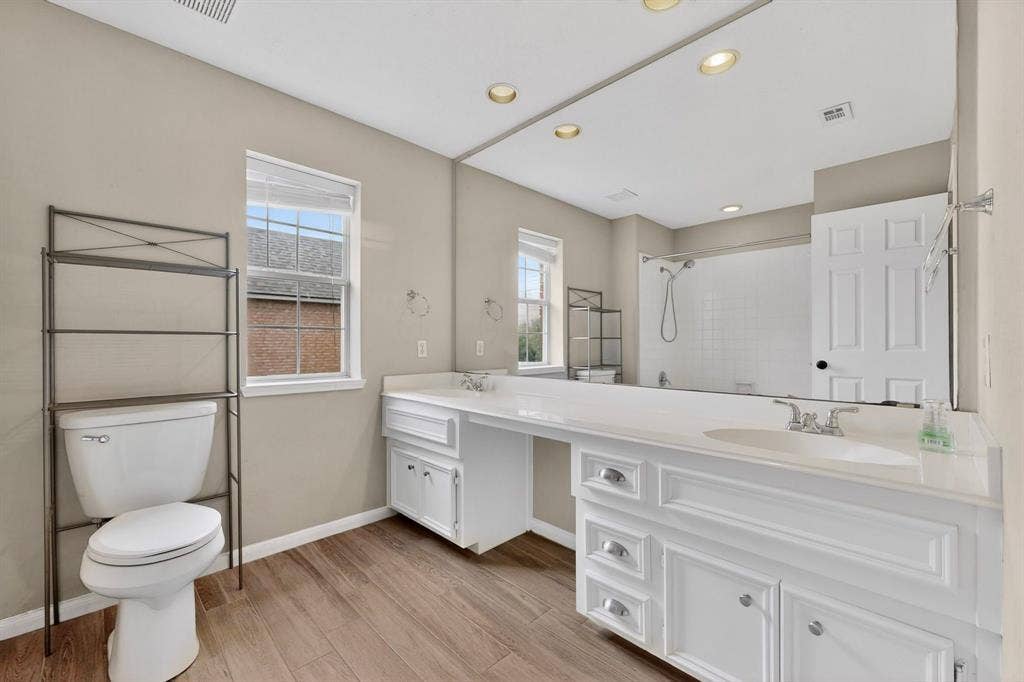 Dual vanity with white cabinetry, wood-finish flooring, recessed lighting, and a built-in shower/tub combination