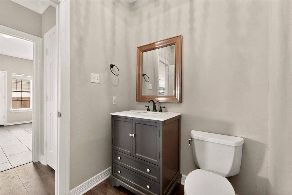 Powder room featuring a dark wood-finish vanity with a white countertop, a rectangular mirror with a wood frame, and wood-finish flooring
