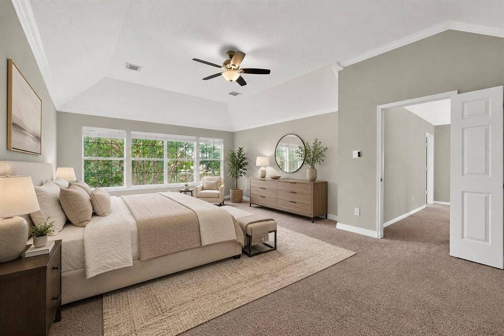 Vaulted ceiling with a ceiling fan, wall-to-wall carpeting, multiple windows, and a panel door